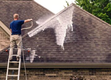 Worker softwashing washing roof